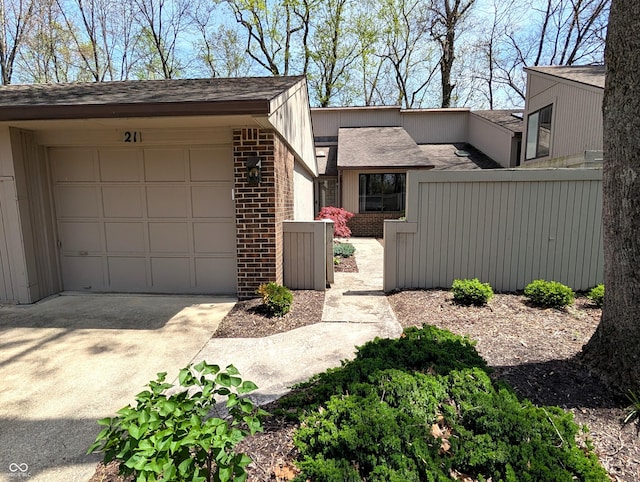 view of home's exterior with driveway, brick siding, fence, an attached garage, and a shingled roof