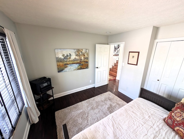 bedroom featuring baseboards, a textured ceiling, dark wood-style flooring, and a closet