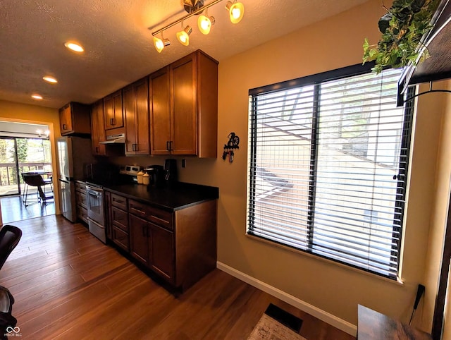 kitchen featuring dark countertops, under cabinet range hood, electric range, and dark wood-style floors