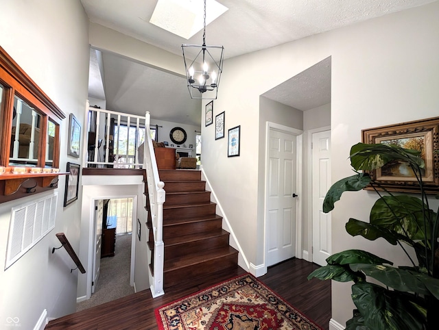 stairway featuring baseboards, wood finished floors, and a notable chandelier