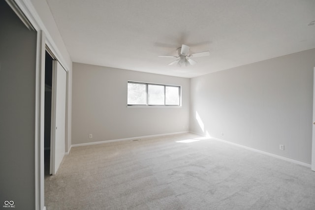 unfurnished bedroom featuring a ceiling fan, light carpet, a closet, and baseboards