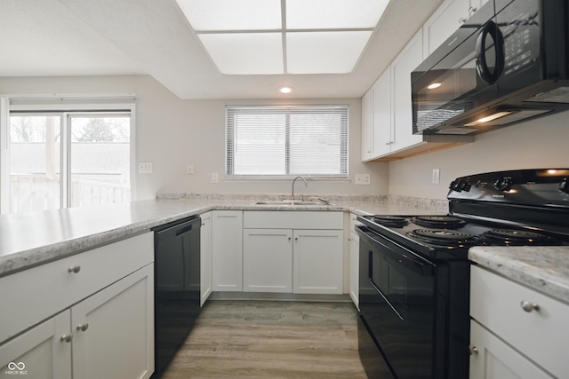 kitchen with plenty of natural light, a sink, white cabinetry, and black appliances