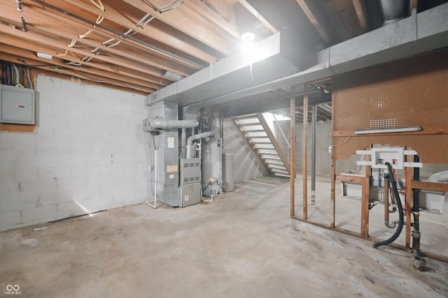 unfinished basement with electric panel, heating unit, water heater, and stairs