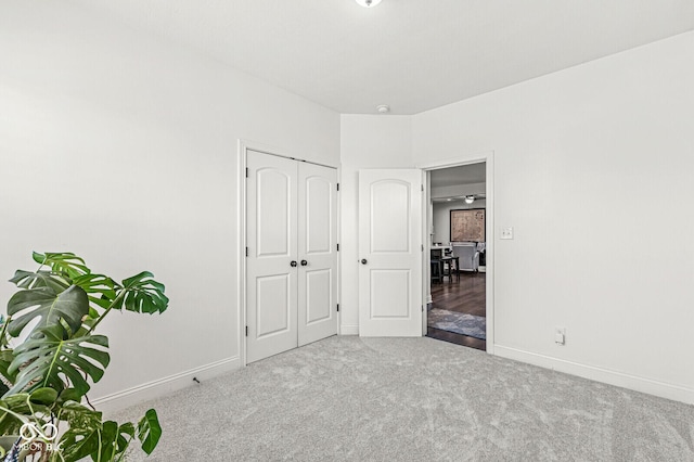 unfurnished bedroom with carpet floors, baseboards, and a closet