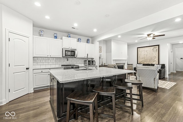kitchen with a kitchen breakfast bar, stainless steel microwave, stove, and tasteful backsplash