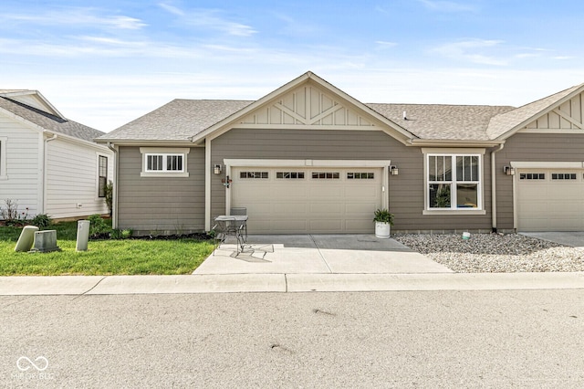 view of front of house with a shingled roof, board and batten siding, an attached garage, and driveway