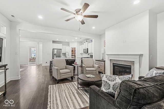 living area featuring ceiling fan, baseboards, dark wood-style floors, recessed lighting, and a premium fireplace