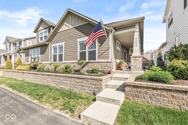 craftsman house with covered porch, board and batten siding, stone siding, and cooling unit