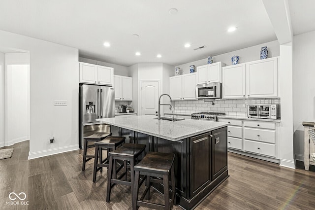 kitchen with decorative backsplash, baseboards, white cabinetry, a sink, and stainless steel appliances