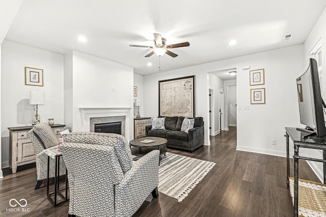 living area featuring visible vents, a ceiling fan, dark wood finished floors, and a fireplace