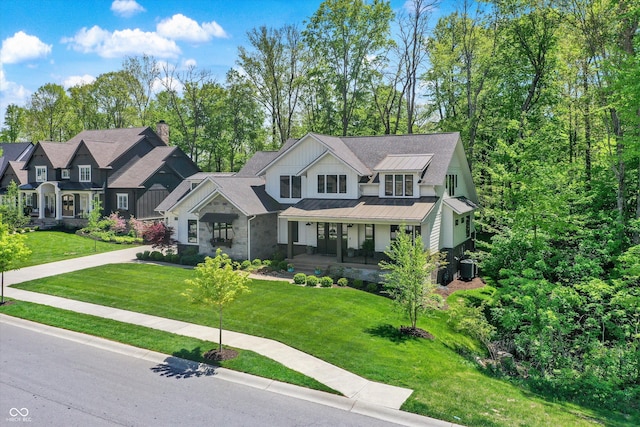 10725 Holliday Farms Blvd, Zionsville, IN 46077 - view of front of house with central AC unit, a front lawn, a standing seam roof, and board and batten siding