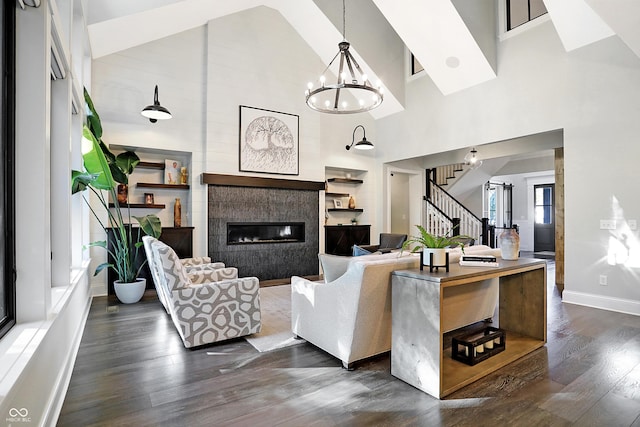 10725 Holliday Farms Blvd, Zionsville, IN 46077 - living room featuring stairs, dark wood finished floors, high vaulted ceiling, a chandelier, and a glass covered fireplace