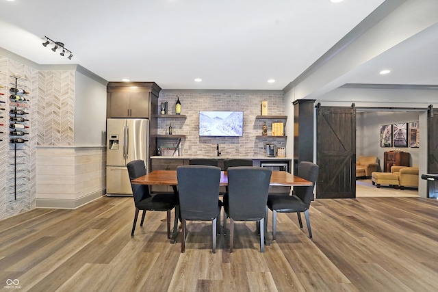 10725 Holliday Farms Blvd, Zionsville, IN 46077 - dining area featuring light wood-style flooring, a barn door, recessed lighting, track lighting, and bar area