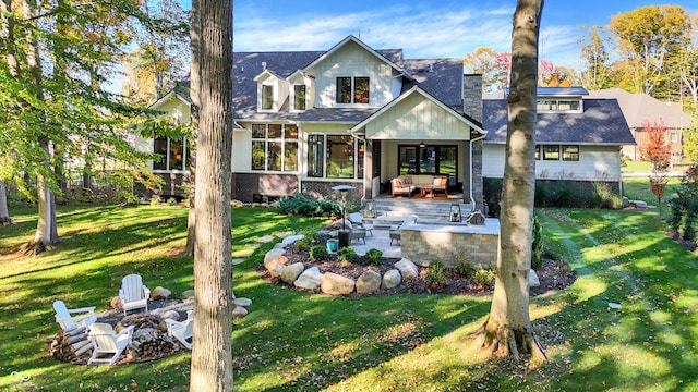 10725 Holliday Farms Blvd, Zionsville, IN 46077 - view of front of home featuring a patio area, an outdoor living space with a fire pit, a front lawn, a sunroom, and a shingled roof