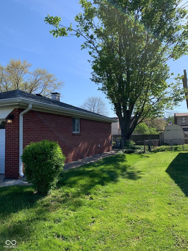view of home's exterior with fence, a chimney, a yard, and brick siding