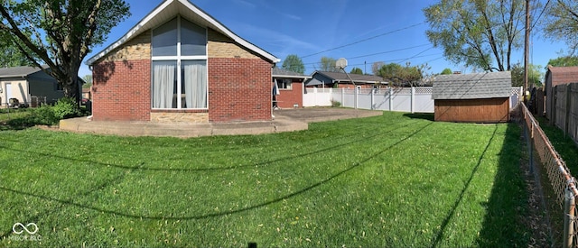 back of house featuring a storage unit, brick siding, a fenced backyard, an outbuilding, and a lawn
