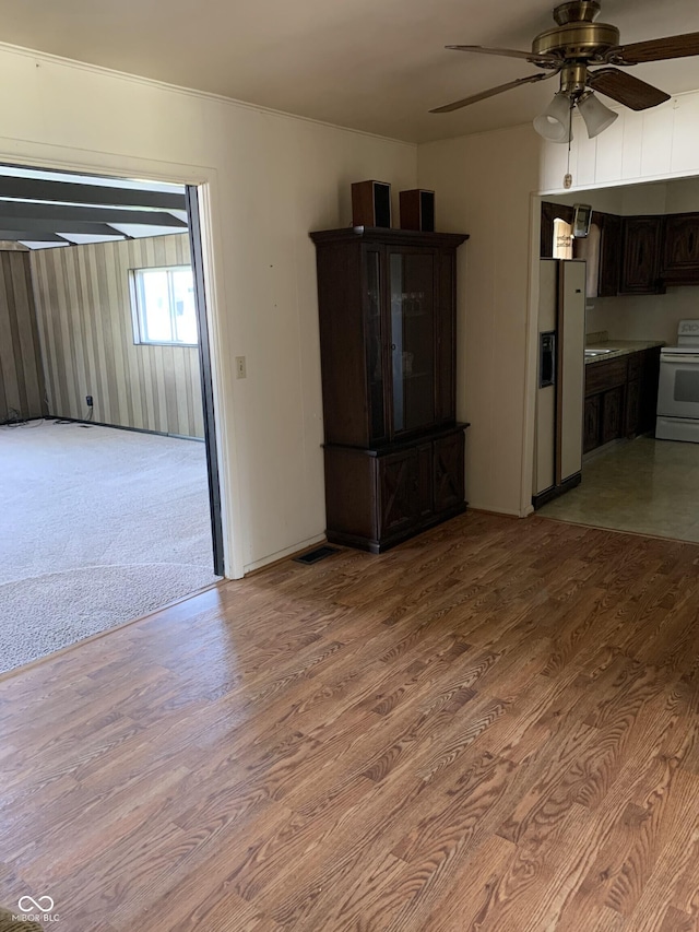 unfurnished living room with crown molding, ceiling fan, and light wood-style floors