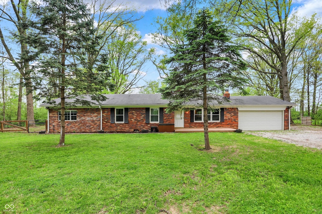 single story home with brick siding, fence, dirt driveway, an attached garage, and a front lawn