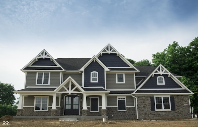 craftsman-style house with brick siding, a shingled roof, and french doors