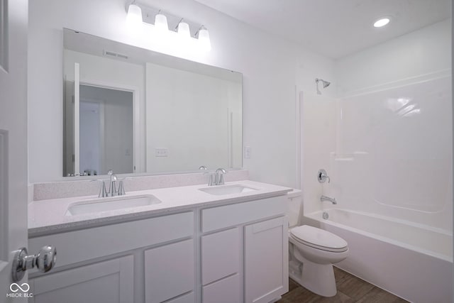 bathroom featuring wood finished floors, a sink, double vanity, and toilet