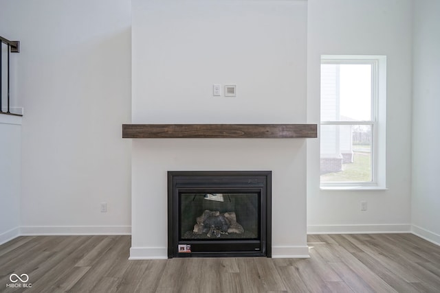 interior details with baseboards, wood finished floors, and a glass covered fireplace