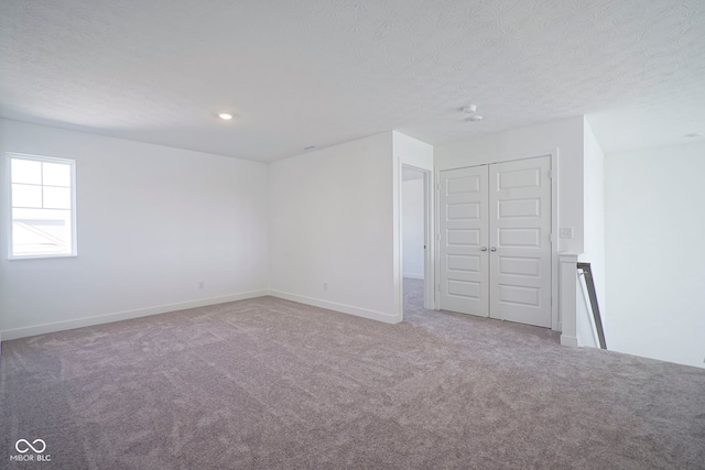 unfurnished bedroom featuring a textured ceiling, baseboards, carpet floors, and a closet