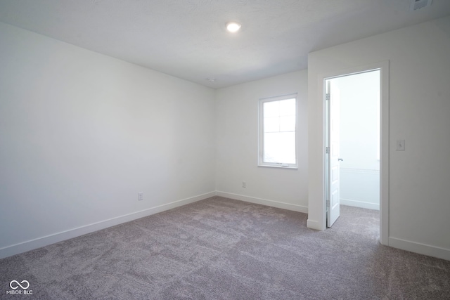 carpeted spare room featuring baseboards