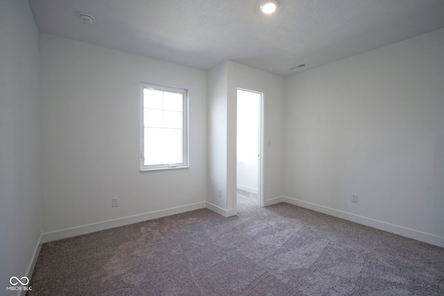 carpeted empty room featuring visible vents and baseboards