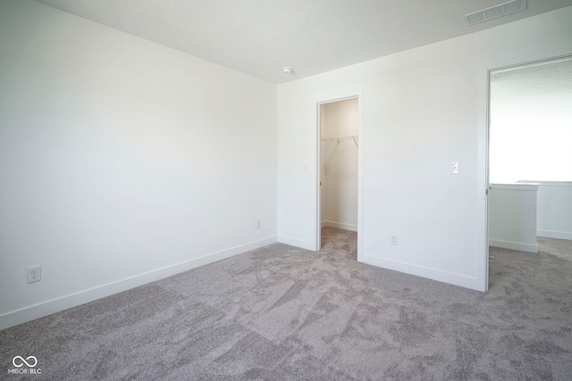 unfurnished bedroom featuring a spacious closet, visible vents, carpet floors, a closet, and baseboards