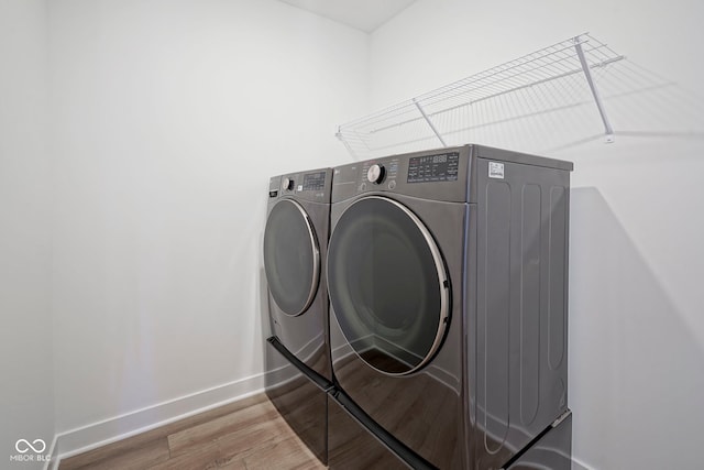 laundry area featuring wood finished floors, baseboards, independent washer and dryer, and laundry area