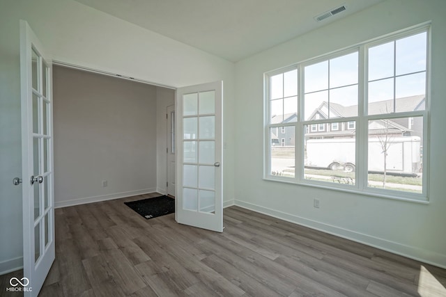 unfurnished room with baseboards, french doors, wood finished floors, and visible vents