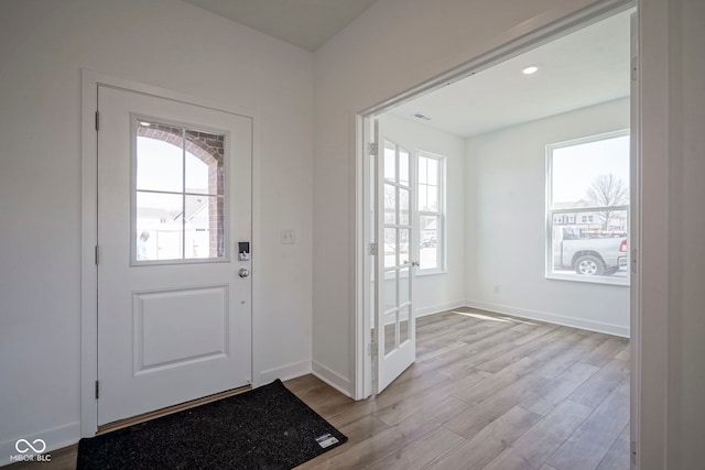 doorway to outside featuring light wood-type flooring, visible vents, and baseboards