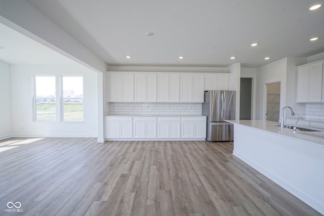 interior space featuring recessed lighting, freestanding refrigerator, tasteful backsplash, and a sink