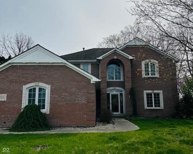 traditional-style home featuring a front lawn and brick siding