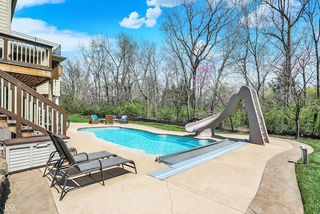 pool with a patio, a water slide, and stairs