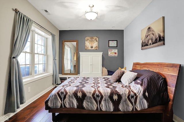 bedroom with baseboards, visible vents, and hardwood / wood-style flooring