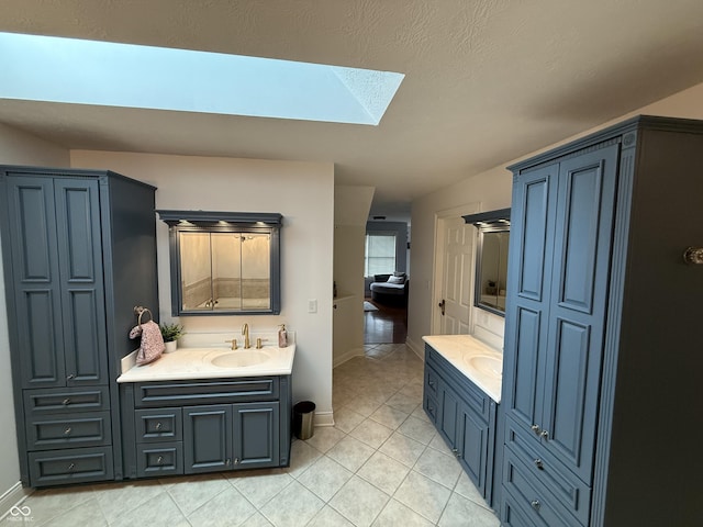 full bathroom featuring a skylight, vanity, baseboards, and tile patterned floors