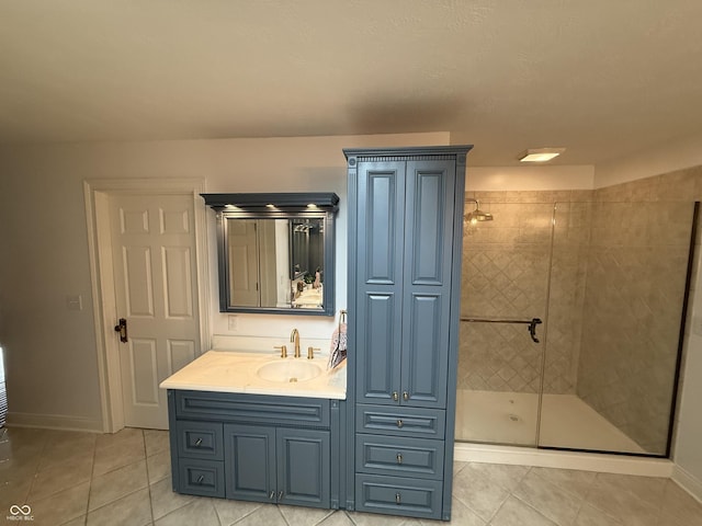 bathroom with tile patterned flooring, baseboards, vanity, and a shower stall