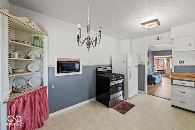kitchen with black microwave, stainless steel range with gas cooktop, light floors, and freestanding refrigerator