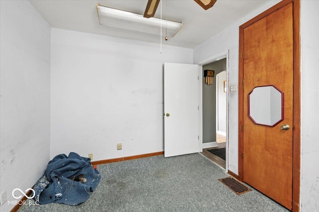 unfurnished bedroom with carpet, attic access, baseboards, visible vents, and a ceiling fan