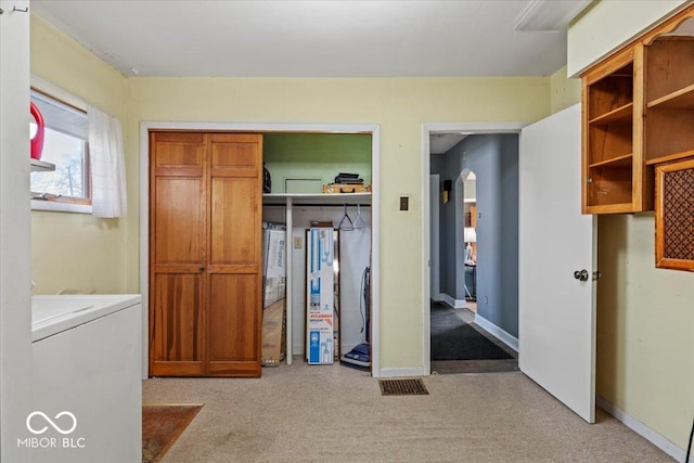unfurnished bedroom with carpet, washer / dryer, arched walkways, and a closet