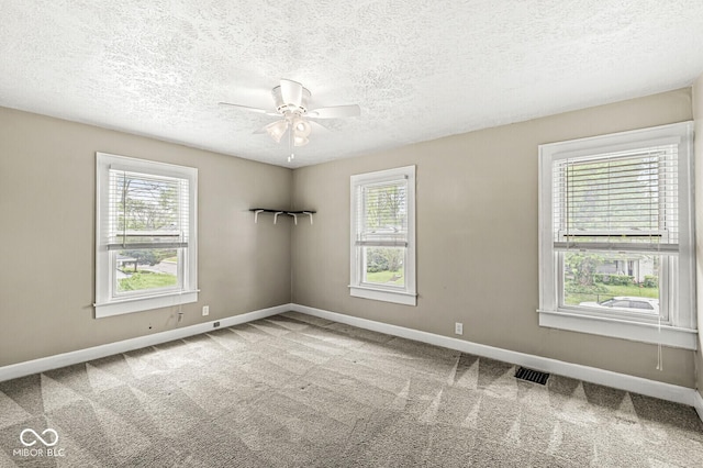 carpeted empty room with baseboards, visible vents, and a wealth of natural light