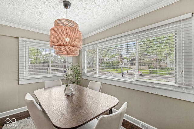 dining area featuring a textured ceiling, baseboards, ornamental molding, and wood finished floors