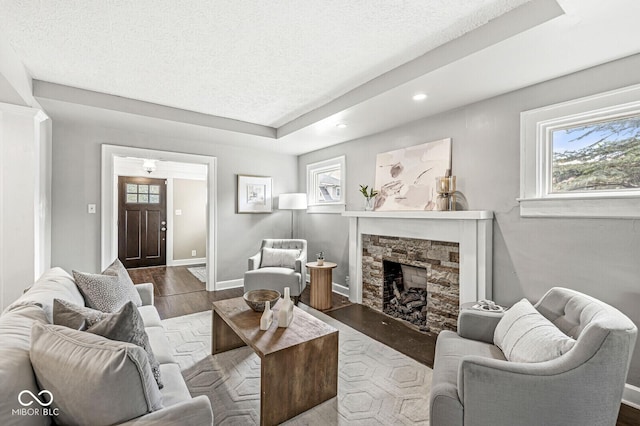 living room with wood finished floors, a fireplace, baseboards, recessed lighting, and a textured ceiling