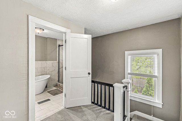 bathroom featuring walk in shower, a textured ceiling, a freestanding tub, tile walls, and visible vents