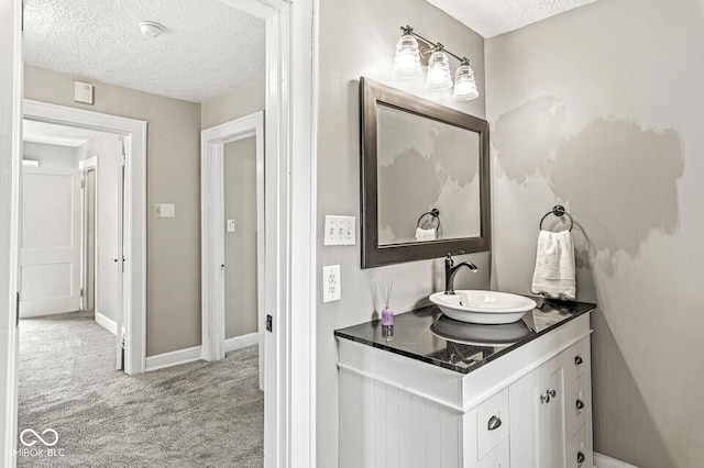 bathroom featuring vanity, a textured ceiling, and baseboards
