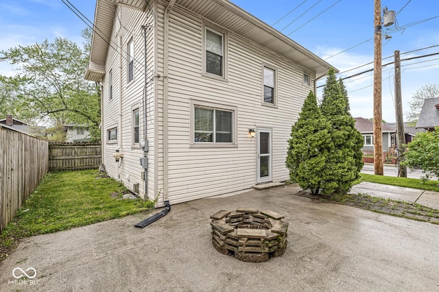 rear view of property featuring a patio, fence, and an outdoor fire pit