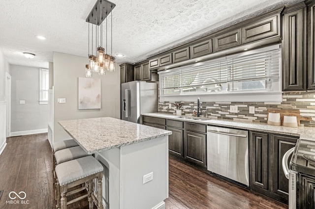kitchen with a center island, tasteful backsplash, dark brown cabinets, a sink, and stainless steel appliances