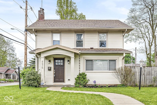 view of front of house featuring fence, a chimney, a shingled roof, and a front lawn