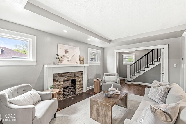 living room featuring plenty of natural light, wood finished floors, stairway, and a fireplace